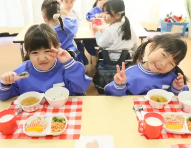 給食を食べながらポーズをとる子ども
