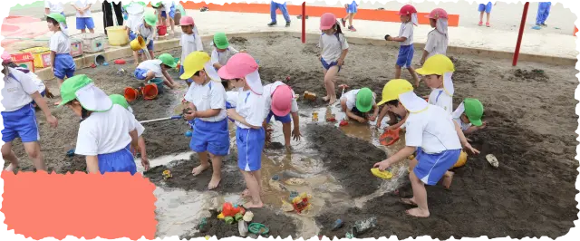 砂場で水を使い泥遊びをする裸足の園児たち