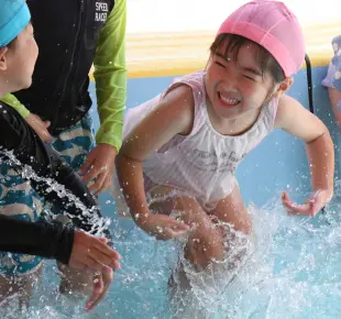 幼稚園のプールで水遊びをする園児たち