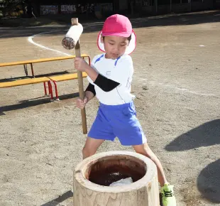 幼稚園の餅つきで杵を振るう男の子