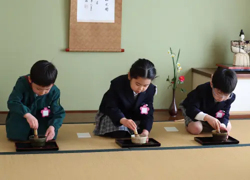 茶道室で正座し、お茶を点てる園児3人