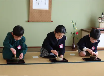 茶道室で正座し、お茶を点てる園児3人