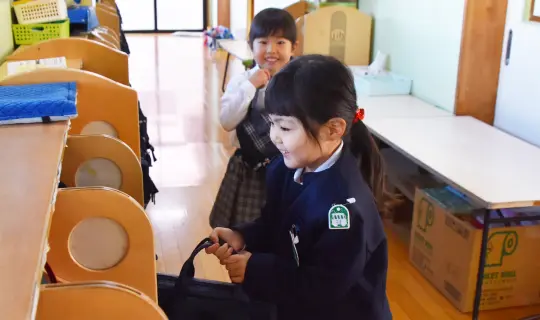 制服を着た女の子がロッカーにリュックを掛ける様子