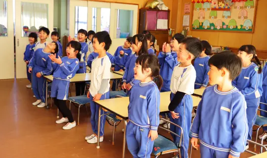 机の横に立ち、先生の話を聞く園児たち