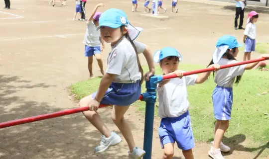 園庭の鉄棒で遊ぶ園児